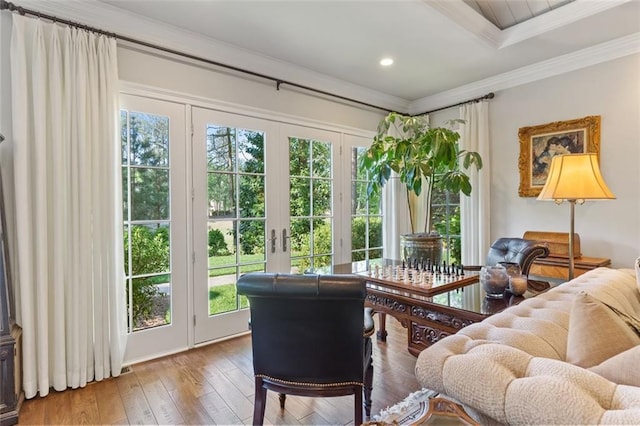 living room featuring french doors, ornamental molding, a raised ceiling, and light wood-type flooring