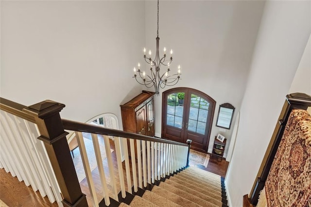 stairs featuring an inviting chandelier, a high ceiling, dark hardwood / wood-style floors, and french doors