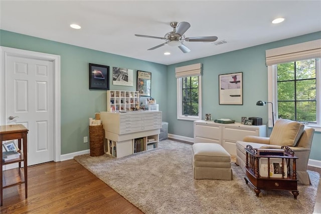 living area featuring ceiling fan, light hardwood / wood-style flooring, and a wealth of natural light