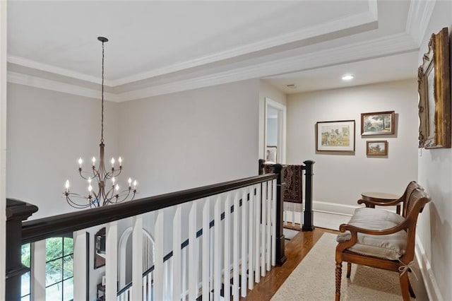 hall featuring an inviting chandelier, ornamental molding, a tray ceiling, and dark hardwood / wood-style flooring