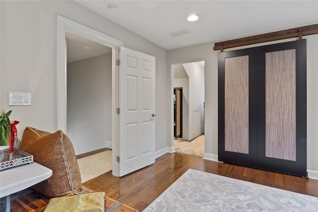 bedroom featuring dark hardwood / wood-style flooring and a barn door