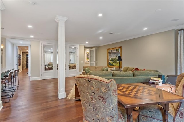 living room with crown molding, dark wood-type flooring, and ornate columns