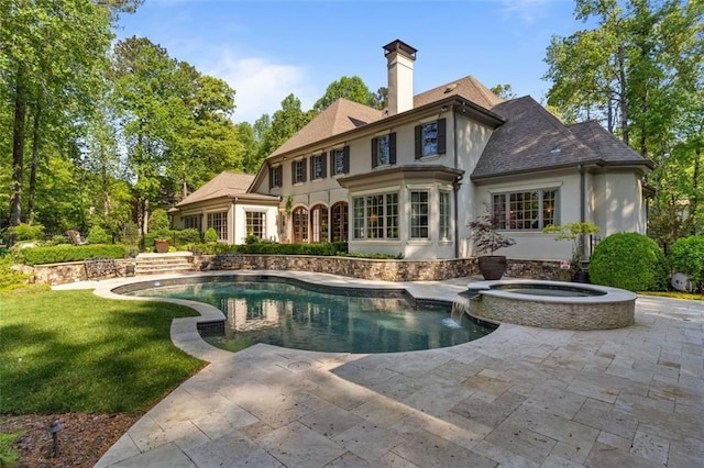 back of property featuring pool water feature, a lawn, a swimming pool with hot tub, and a patio