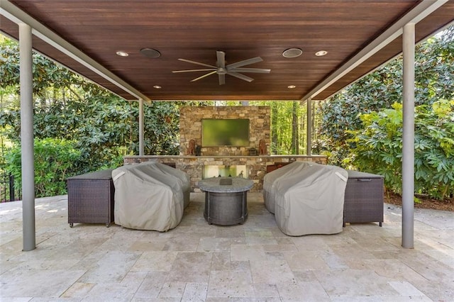 view of patio / terrace with an outdoor stone fireplace, ceiling fan, and area for grilling