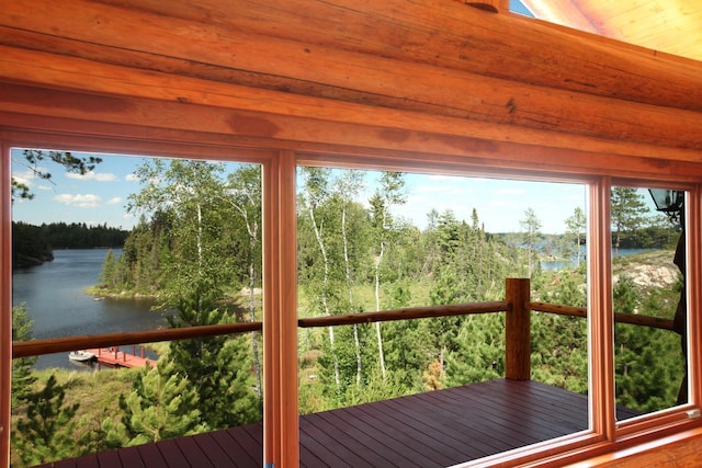 unfurnished sunroom featuring a water view and a view of trees