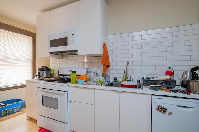 kitchen featuring white appliances, light wood-type flooring, sink, and a wealth of natural light