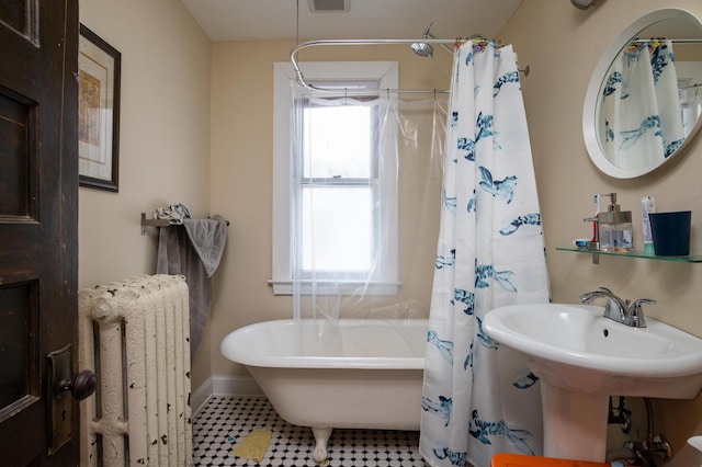 bathroom with tile floors, radiator heating unit, and a healthy amount of sunlight