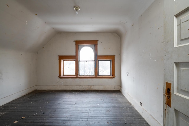additional living space featuring dark wood-type flooring and vaulted ceiling