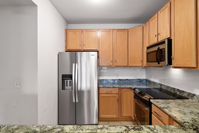 kitchen with appliances with stainless steel finishes, backsplash, dark stone countertops, light tile floors, and a textured ceiling