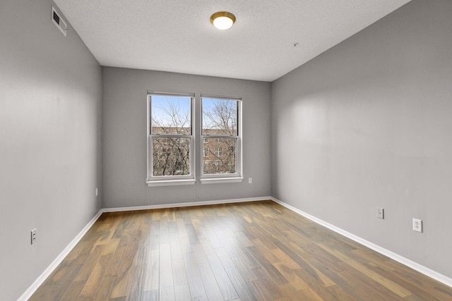 unfurnished room featuring a textured ceiling and dark hardwood / wood-style floors