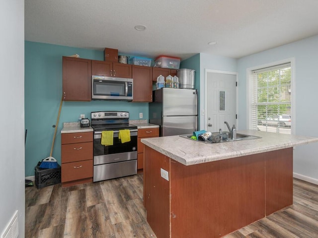 kitchen featuring appliances with stainless steel finishes, dark hardwood / wood-style floors, sink, and an island with sink