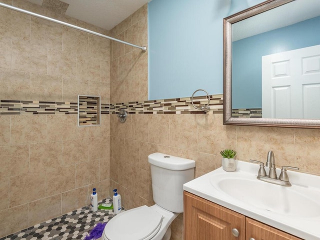 bathroom featuring tile walls, backsplash, toilet, vanity, and a tile shower