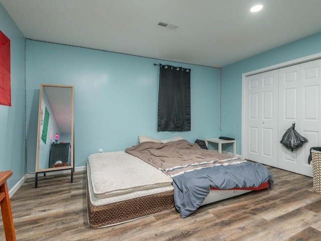 bedroom with dark hardwood / wood-style flooring and a closet