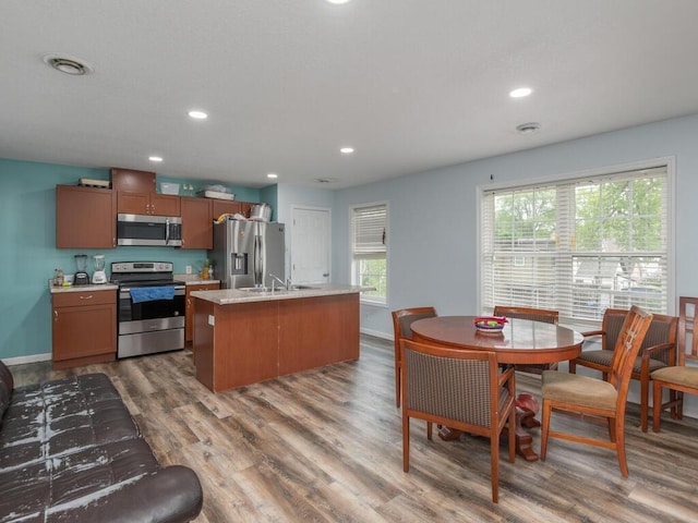 kitchen featuring appliances with stainless steel finishes, sink, a center island with sink, and wood-type flooring