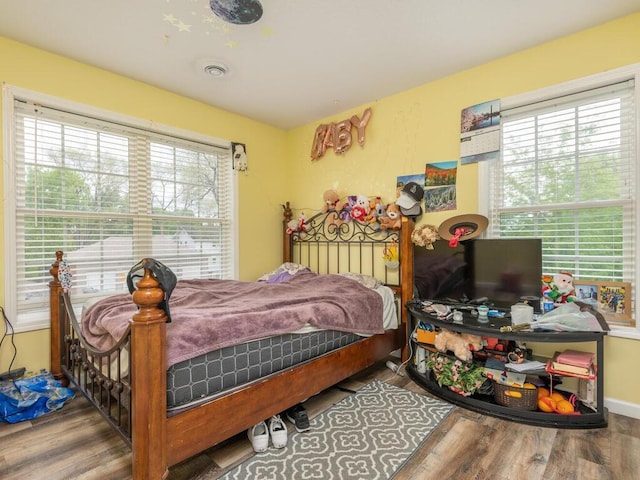 bedroom with multiple windows and dark wood-type flooring