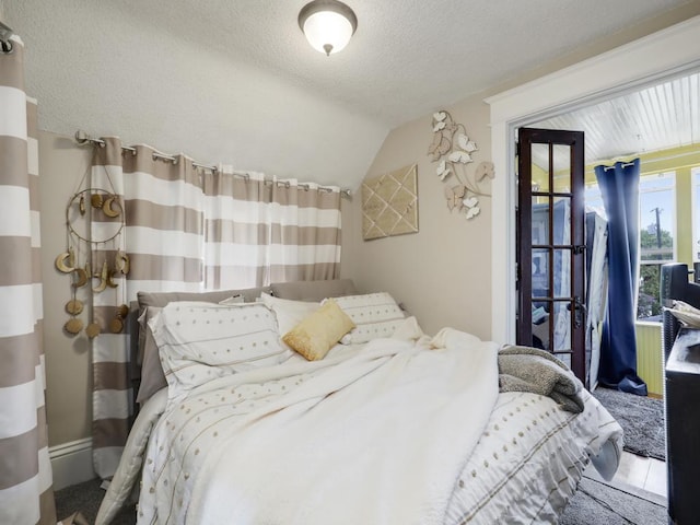 bedroom featuring lofted ceiling, access to exterior, carpet, and a textured ceiling