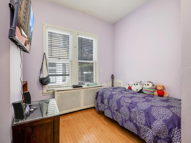 bedroom with radiator heating unit and light hardwood / wood-style floors