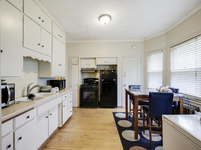 kitchen featuring light hardwood / wood-style floors, white cabinetry, crown molding, black appliances, and sink