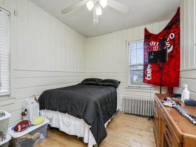 bedroom with light wood-type flooring, ceiling fan, and radiator