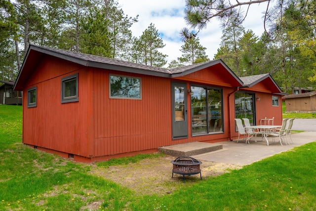 back of house featuring a fire pit, a patio area, and a lawn