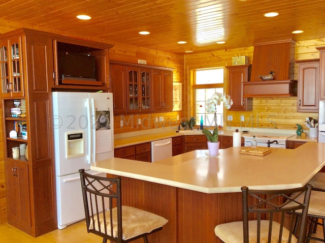 kitchen with white appliances, wood ceiling, a breakfast bar area, and wooden walls