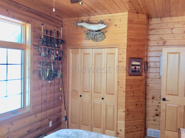 bedroom with wood ceiling, multiple windows, and wood walls