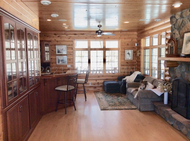24557 Walden Rd, Rochert, MN 56578 - living room featuring rustic walls, light wood-style floors, a ceiling fan, wood ceiling, and a stone fireplace