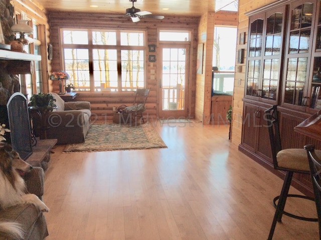 living room with log walls, wood ceiling, light hardwood / wood-style floors, and ceiling fan