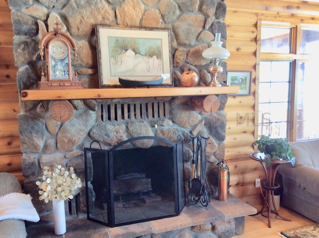 interior details with a stone fireplace, wood-type flooring, and log walls