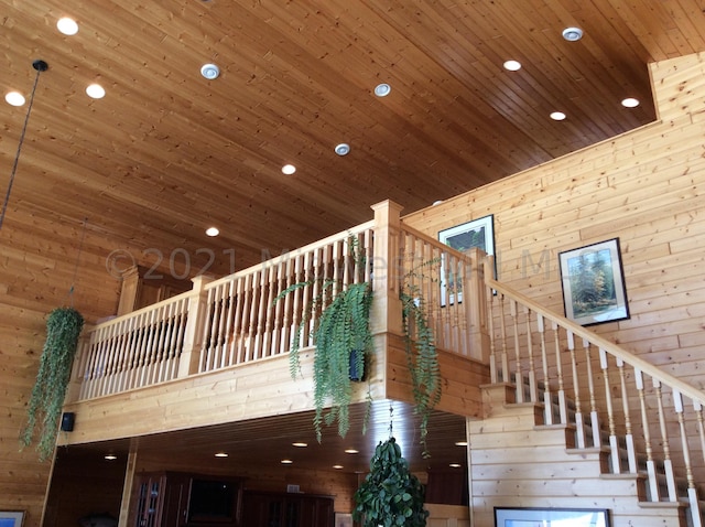 interior space with wooden ceiling, a towering ceiling, and wooden walls