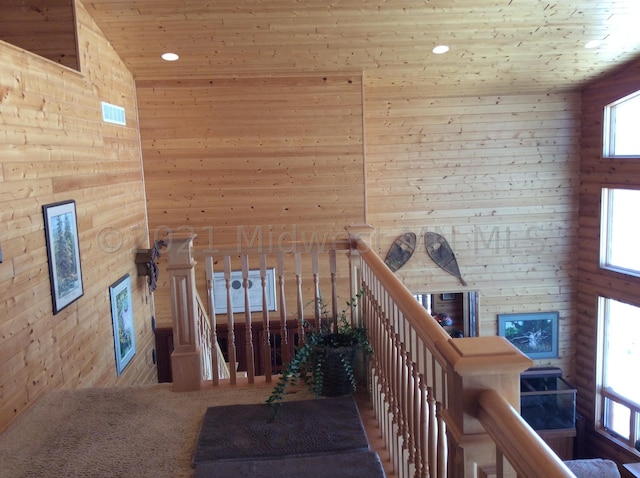 staircase featuring a towering ceiling, wooden ceiling, and wood walls