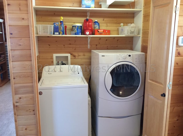 laundry room with wood walls, carpet, and washer and clothes dryer