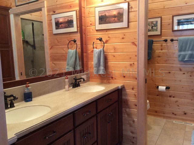 bathroom featuring wood walls, toilet, tile patterned flooring, vanity, and an enclosed shower