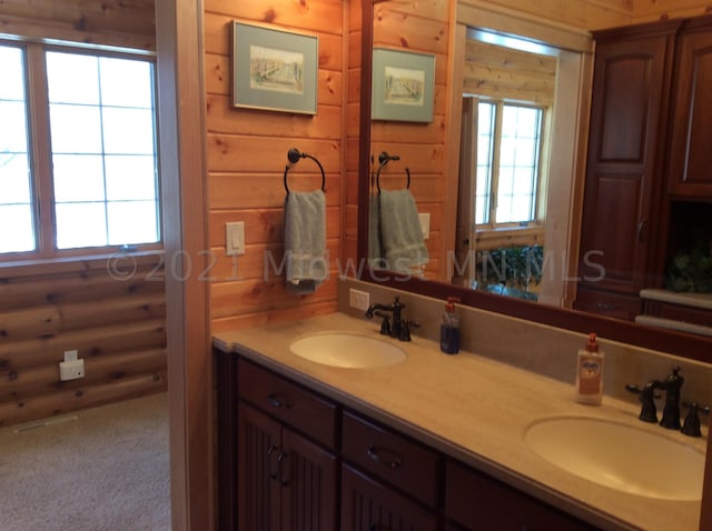 bathroom featuring vanity, rustic walls, a healthy amount of sunlight, and wood walls