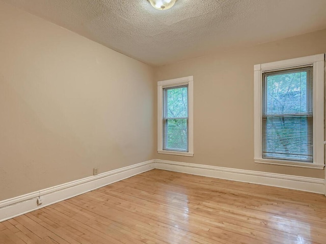 spare room featuring light hardwood / wood-style floors and a textured ceiling