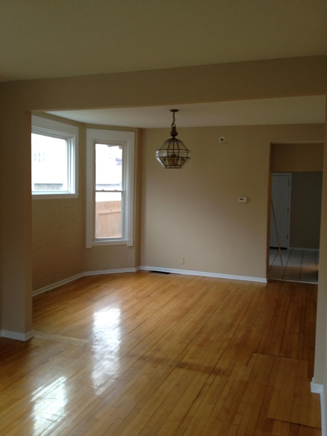 empty room with an inviting chandelier and light wood-type flooring