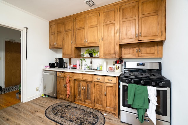 kitchen featuring stainless steel appliances, light hardwood / wood-style flooring, sink, and crown molding