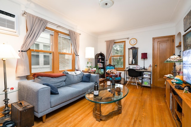 living room with a wall mounted AC and light hardwood / wood-style flooring