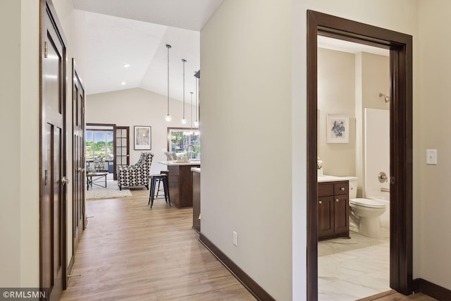 hall featuring lofted ceiling and light hardwood / wood-style flooring