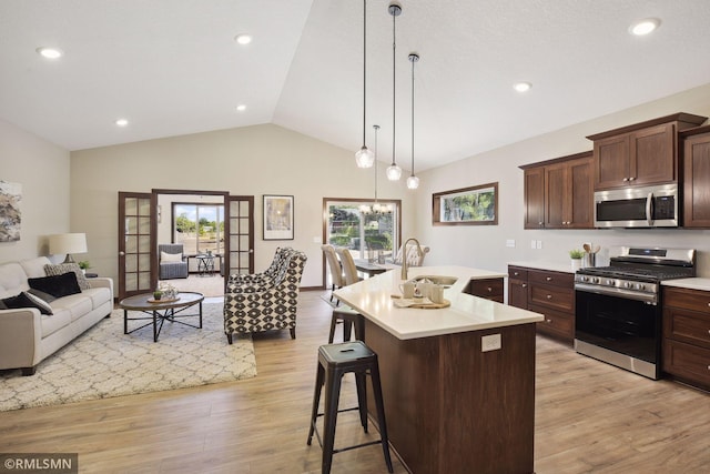 kitchen featuring hanging light fixtures, appliances with stainless steel finishes, a breakfast bar, light hardwood / wood-style floors, and sink