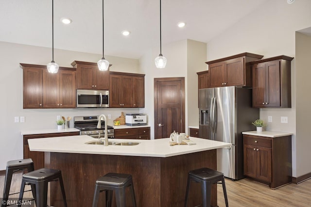 kitchen featuring a kitchen bar, appliances with stainless steel finishes, light wood-type flooring, and pendant lighting