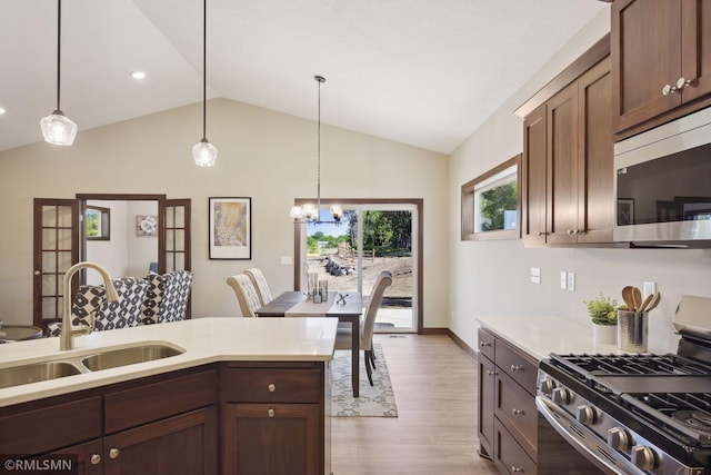 kitchen with lofted ceiling, light hardwood / wood-style flooring, stainless steel appliances, and pendant lighting