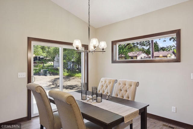 dining area with plenty of natural light, dark wood-type flooring, high vaulted ceiling, and a chandelier