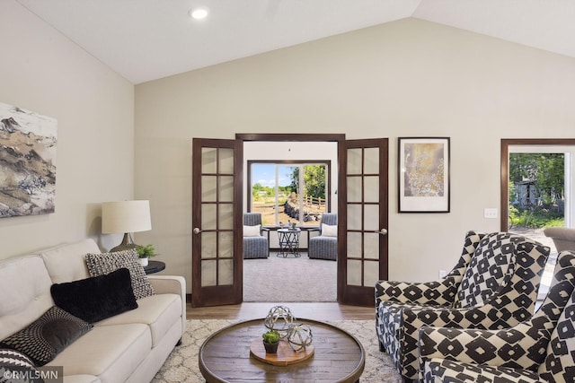 living room with lofted ceiling, french doors, and light wood-type flooring