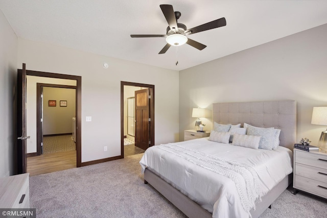 bedroom with ceiling fan, light colored carpet, and ensuite bathroom