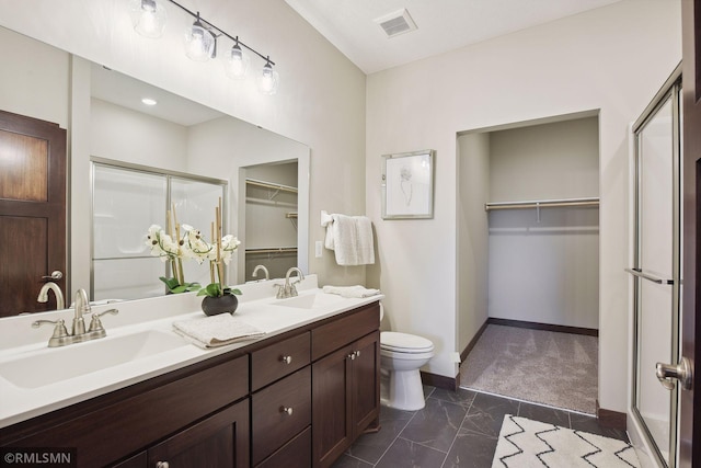 bathroom featuring toilet, double vanity, tile flooring, and a shower with shower door