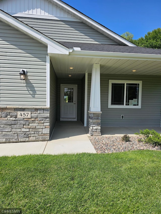 entrance to property with a porch and a yard