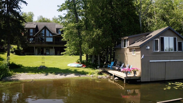 back of house with a water view and a yard