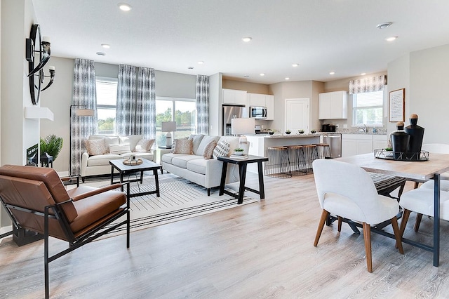 living room featuring light wood-type flooring, sink, and plenty of natural light