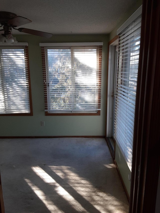 carpeted empty room with ceiling fan and a textured ceiling